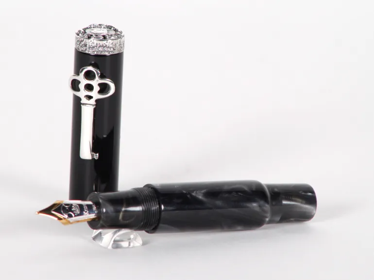 قلم حبر Krone Pens IB02922 Houdini من السيلولويد الأسود مع زخرفة فضية وريشة ذهب 18 قيراط، مع ظهور الغطاء والجسم.