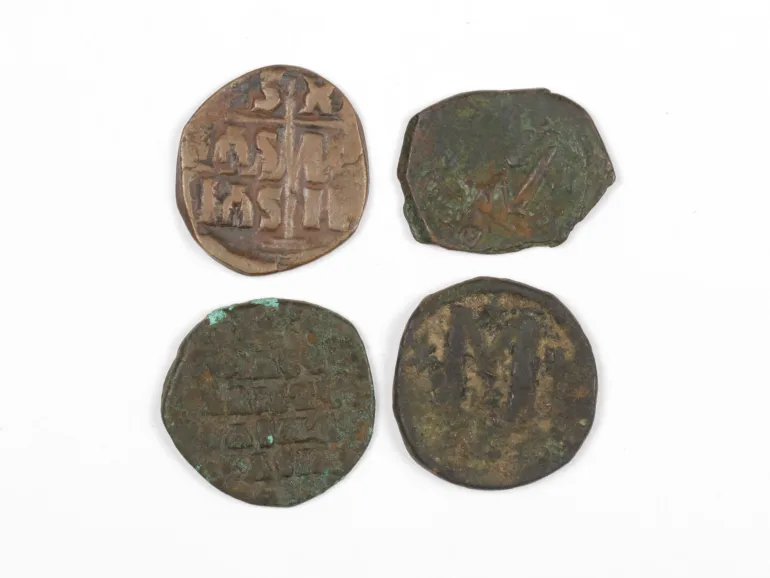 IB03570 : quatre pièces byzantines en bronze, dont une avec une croix, sur fond blanc.