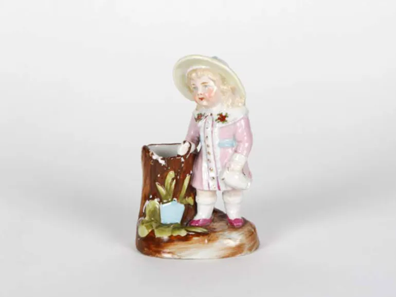 IB05065 porcelain sculpture of a girl in a pink dress with a basket, shown on a base; painted and enameled, late 19th century.