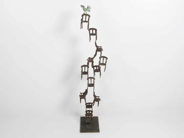 IB05729, sculpture en bronze de Monkith Saaid montrant une pile de chaises surmontée d’un coq, sur socle.