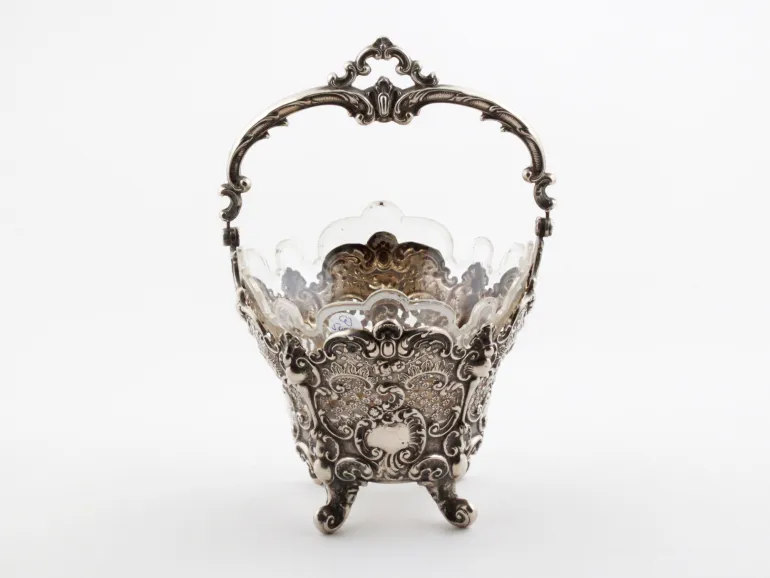 IB08127 Victor Nuber sterling silver basket with ornate handle, four feet, and glass insert, shown on white background.