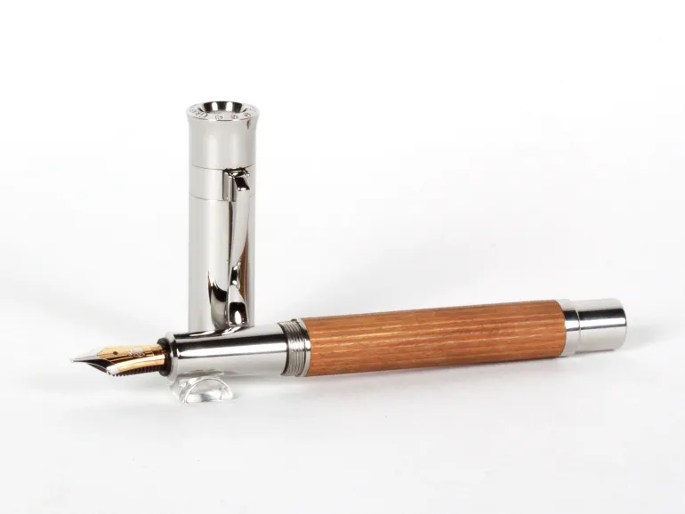 Stylo plume Faber Castell IB08538 avec corps en bois d’olivier, capuchon plaqué argent et plume dorée, capuchon posé à côté du stylo.