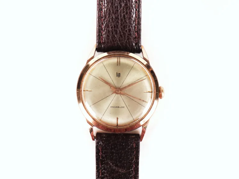 Montre bracelet LIP, SKU IB09481, avec boîtier rond doré, cadran argenté et bracelet en cuir foncé, vue de face.