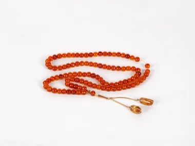 IB03684 Masbaha rosary in Polish amber with 99 amber beads and a copper-gold pendant with two stones, shown on a white background.