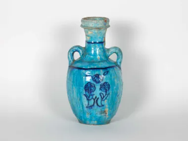 IB06023: Two-handled turquoise glazed ceramic amphora with floral decoration, shown against a white background.
