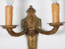 SKU IB01173 : Paire d'appliques de style Louis XVI en bronze doré à deux branches, avec ampoules façon bougie, sur fond blanc.