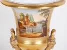 IB01870 Pair of 19th-century Médicis porcelain vases, shown close up with gilded rim, painted landscape panel, and bearded face handles.