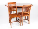 Table de salle à manger Marine Type IB02322 avec plateau ovale en noyer et deux chaises en bois à barreaux.
