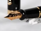 Aurora Talentum fountain pen, SKU IB02724, black lacquer with gold trim and 14K gold nib shown close up.