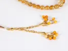 IB03618 Masbaha rosary with natural topaz beads and gold pendant, shown with amber-toned round stones and gold chains on a white background.