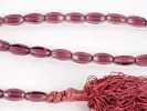 IB03620: close-up of an amethyst-colored glass masbaha rosary with oval beads and a braided thread tassel.