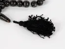 IB03630 Black Coral Masbaha rosary with black spotted beads and braided black tassel on white background.