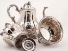 طقم شاي Wood & Hughes من الفضة الإسترليني، SKU IB04739، يظهر إبريق شاي ووعاء بغطاء ووعاء مزخرفين بنقوش زهرية.