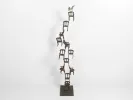IB05729 de Monkith Saaid : sculpture en bronze patiné représentant une pyramide de chaises surmontée d’un coq, sur fond blanc.