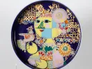 قطعة وسط طاولة روزنتال Bjorn Wiinblad، SKU IB07504، طبق زخرفي من الخزف المطلي بوجهٍ أسلوبي ملوّن ونقوش ذهبية على خلفية زرقاء داكنة.