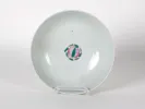 Chinese Kangxi period porcelain bowl, IB08581, white with a small pink and green floral motif, shown on a stand.