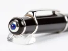 Cartier Diabolo ballpoint pen, SKU IB08934, black resin with platinum trim and blue cabochon end, shown on a clear stand.