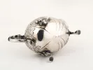 IB09116 18th-century Irish sterling silver sauceboat with one handle, floral engraving, three feet, and a coat of arms.