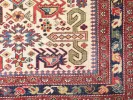 IB09734 Caucasian Chirvan Kuba Perpedil wool rug with geometric motifs, flowers and stylized animal forms, shown in a close-up of the woven pattern.