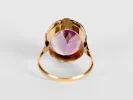 Gold ring with a purple gemstone, captured from a top-down angle.
